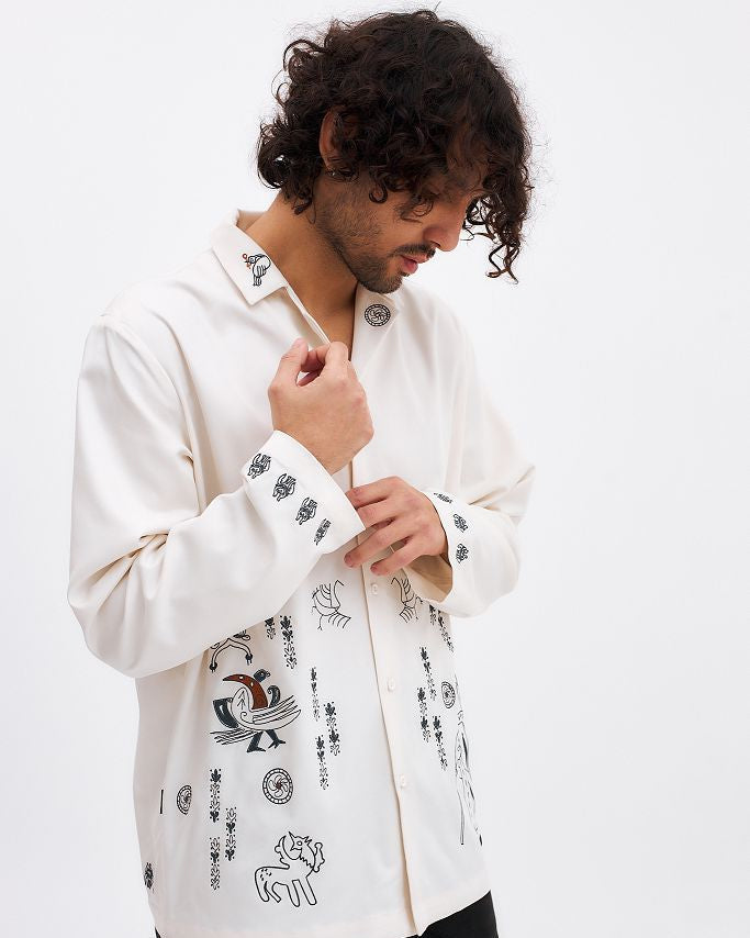 Man wearing a white embroidered shirt against a white background