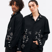 Two people wearing black embroidered jackets on a white background