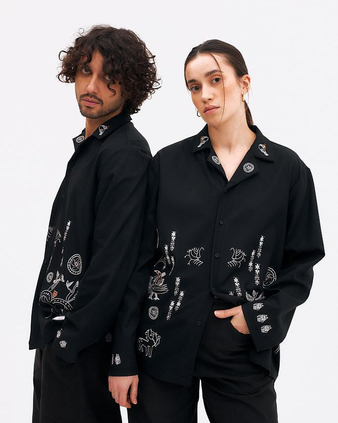 Two people wearing black embroidered jackets on a white background