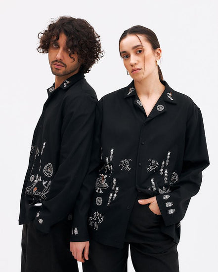 Two people wearing black embroidered jackets on a white background