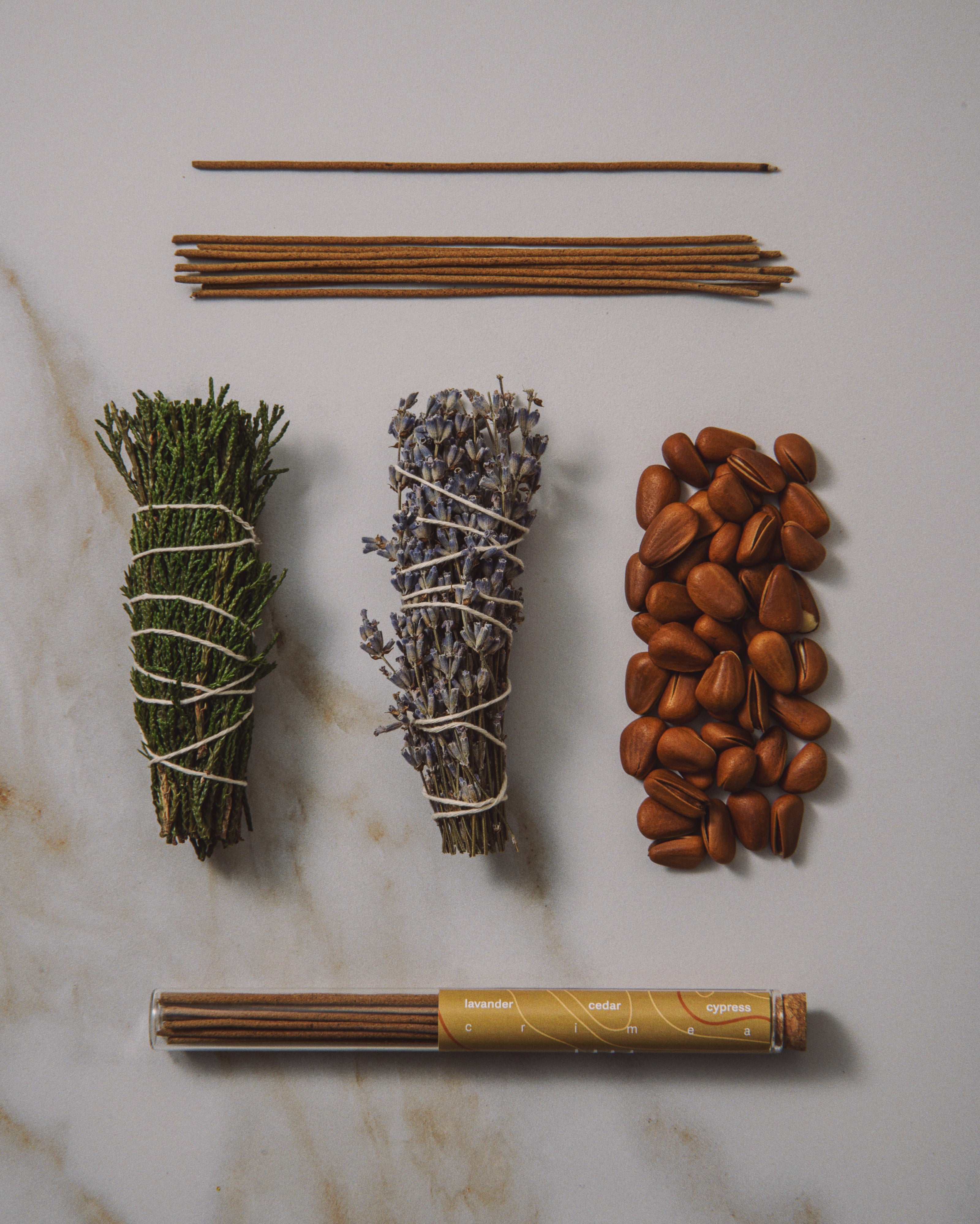Collection of incense sticks, sage, lavender, and other herbs on a marble surface