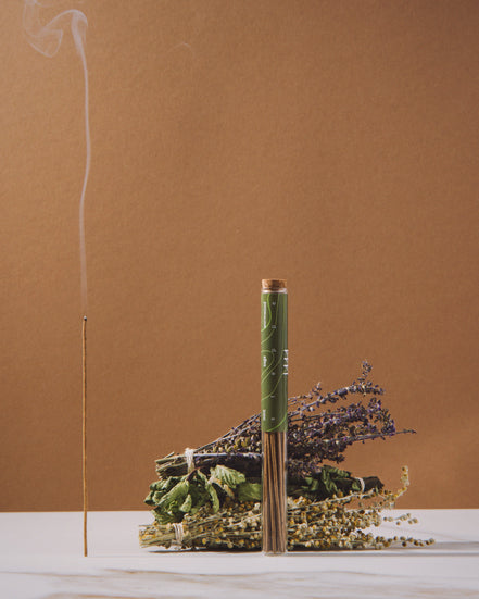 Incense stick with smoke and decorative elements on a brown background