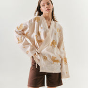 Woman wearing a white kimono with gold patterns on a plain background