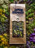 Herbal tea package surrounded by various herbs and flowers