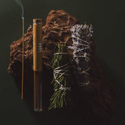 Incense stick, bamboo tube, and dried herbs on a dark background