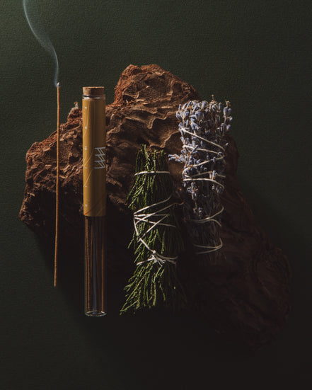 Incense stick, bamboo tube, and dried herbs on a dark background