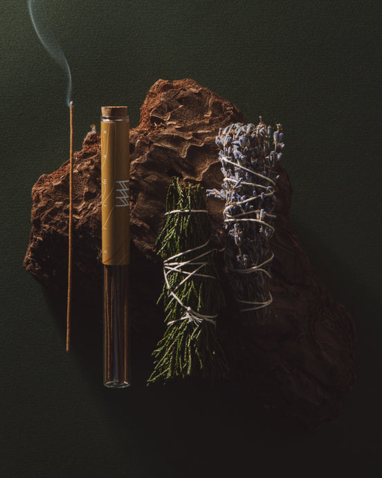 Incense stick, bamboo tube, and dried herbs on a dark background