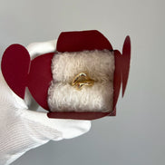 Gold ring in a red heart-shaped box on a light gray background