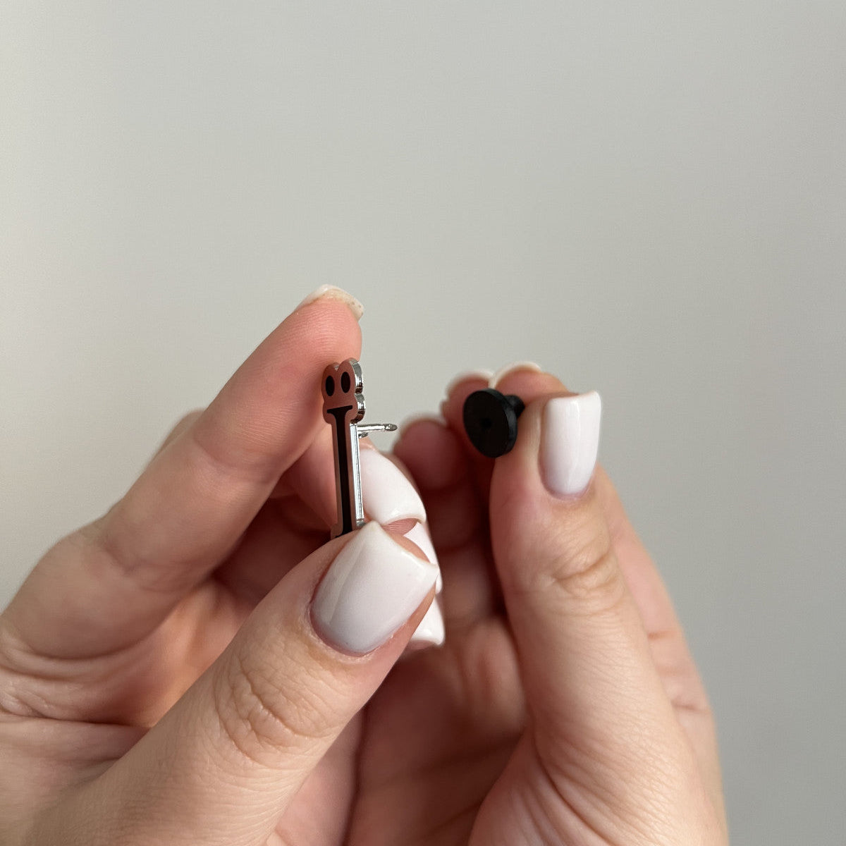 Hand holding a small black object against a plain background