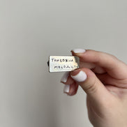 Hand holding a small rectangular object with text against a plain background