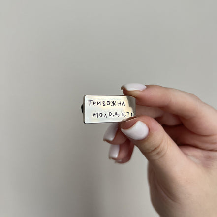 Hand holding a small rectangular object with text against a plain background