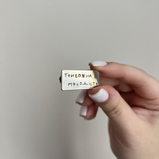 Hand holding a small rectangular object with text against a plain background