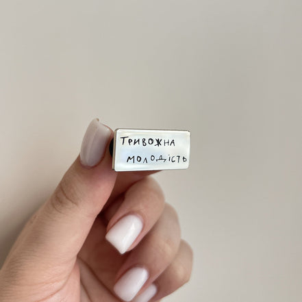Hand holding a small rectangular white object with text on a plain background