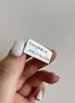 Hand holding a small rectangular metal object with engraved text on a plain background
