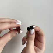 Close-up of a hand holding two small objects against a plain background