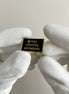 Pin with 'Free Azovstal Defenders' text held by white gloves on a light background