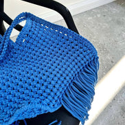 Blue knitted bag with fringe on a chair