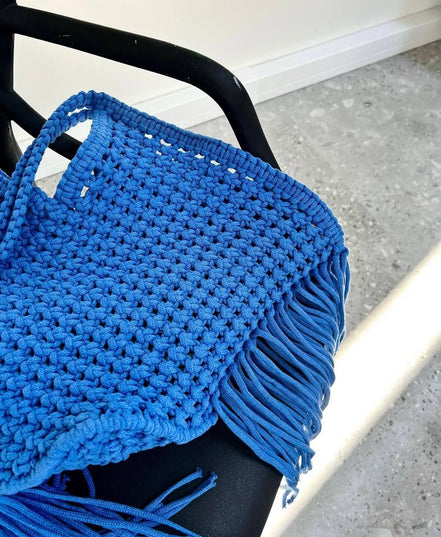 Blue knitted bag with fringe on a chair