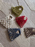 Five small woven bags in different colors on a textured fabric background