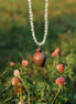 Necklace with a brown pendant hanging over flowers in a field