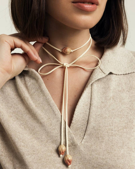 Necklace with a central pendant worn by a person in a neutral setting