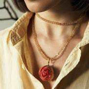 Close-up of a person wearing a necklace with a red pendant.