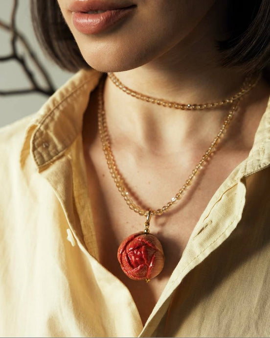 Close-up of a person wearing a necklace with a red pendant.