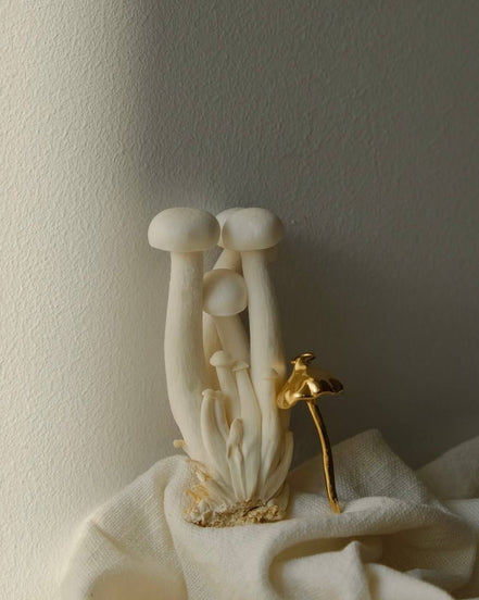 Mushroom-shaped faucet with gold handle on a neutral background