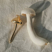 Mushroom-shaped earrings on a textured fabric background
