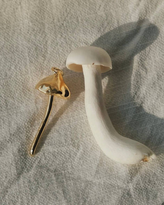 Mushroom-shaped earrings on a textured fabric background