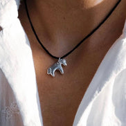 Necklace with a horse pendant worn by a person in a white shirt.